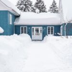 image of a blue house in several feet of snow